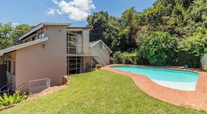 A two-story house with a swimming pool, a covered patio, and a well-maintained lawn. - Family sized house (Pretoria)