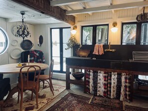 Una cocina rústica con una mesa de madera, sillas, una araña y un ventanal grande.