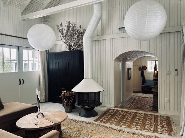 A room with a fireplace, a black wardrobe, a round wooden table, and a patterned rug.