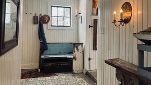 Tunnelmallinen huone, jossa on puinen penkki, ikkuna, seinään kiinnitetty valaisin ja peili.