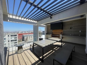 A rooftop terrace with a table and chairs, a flat-screen TV, and a view of the cityscape. - RBK moderno Studio pasos de Club Hípico (Santiago)
