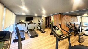 A gym with treadmills, an elliptical, and a stationary bike. - RBK moderno Studio pasos de Club Hípico (Santiago)