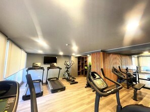 A gym with treadmills, elliptical machines, and a weight bench. - RBK moderno Studio pasos de Club Hípico (Santiago)