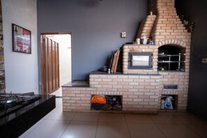 A kitchen with a brick oven, a gas stove, and a door leading to another room. - Casa com Piscina e Churrasqueira Perto do Centro (Uberlandia)