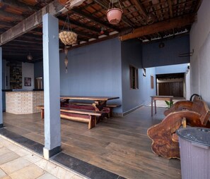 A spacious patio area with wooden benches, a trash bin, and hanging baskets. - Casa com Piscina e Churrasqueira Perto do Centro (Uberlandia)