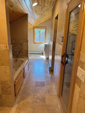 Un baño estrecho con bañera, ventana y perchero.