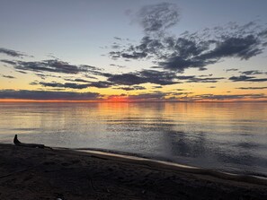 Una playa con un atardecer, agua tranquila y cielo despejado.