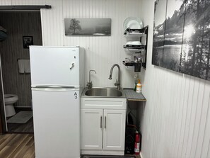 Une cuisine de taille réduite, avec un réfrigérateur blanc, un évier et un petit plan de travail.