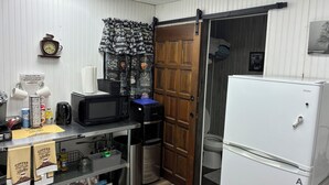 A compact kitchen with a microwave, coffee maker, and a refrigerator.