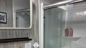 A bathroom with a white sink, mirror, and a glass shower enclosure.