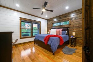 Ein Schlafzimmer mit Bett, Nachttisch, Fenster und Deckenventilator.