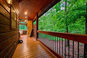 Eine Holzhütte mit Veranda, Steinmauer und Blick auf einen Wald.