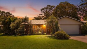 Una casa con garage, immersa nel verde e alberi.