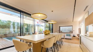 A modern kitchen with a large island, bar stools, pendant lighting, and a view of the outdoors. - Villa Émeraude: A stunning villa located 150 meters from the beach. (Arcachon)