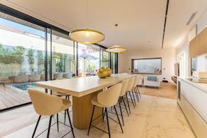 A modern kitchen with a large island, bar stools, pendant lighting, and a view of the outdoors.