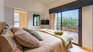 A bedroom with a bed, a TV, a sliding glass door to a balcony, and a marble wall. - Villa Émeraude: A stunning villa located 150 meters from the beach. (Arcachon)