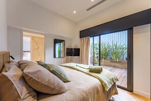 A bedroom with a bed, a TV, a sliding glass door to a balcony, and a marble wall.