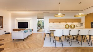 A modern living room with a sofa, TV, and dining area with chairs and a table. - Villa Émeraude: A stunning villa located 150 meters from the beach. (Arcachon)