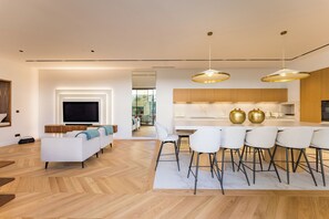 A modern living room with a sofa, TV, and dining area with chairs and a table.