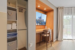 A room with a wooden desk, a chair, a television displaying a castle, and a large window with curtains. - Studio near Universal, Epic & I-Drive (Orlando)