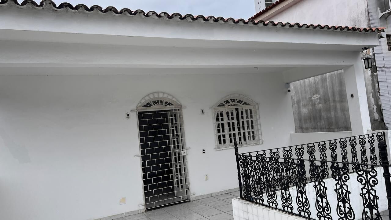 Un bâtiment blanc avec un toit en tuiles, un portail en métal et une rampe en fer forgé décorative.