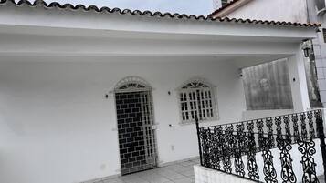 Un bâtiment blanc avec un toit en tuiles, un portail en métal et une rampe en fer forgé décorative.