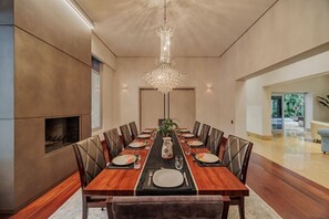 Ein Esszimmer mit einem langen Holztisch, Ledersesseln, einer Kristallleuchter und einem Kamin.