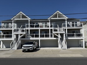 Ein mehrgeschossiges Wohngebäude mit weißer Fassade, mehreren Balkonen und einer Garage.