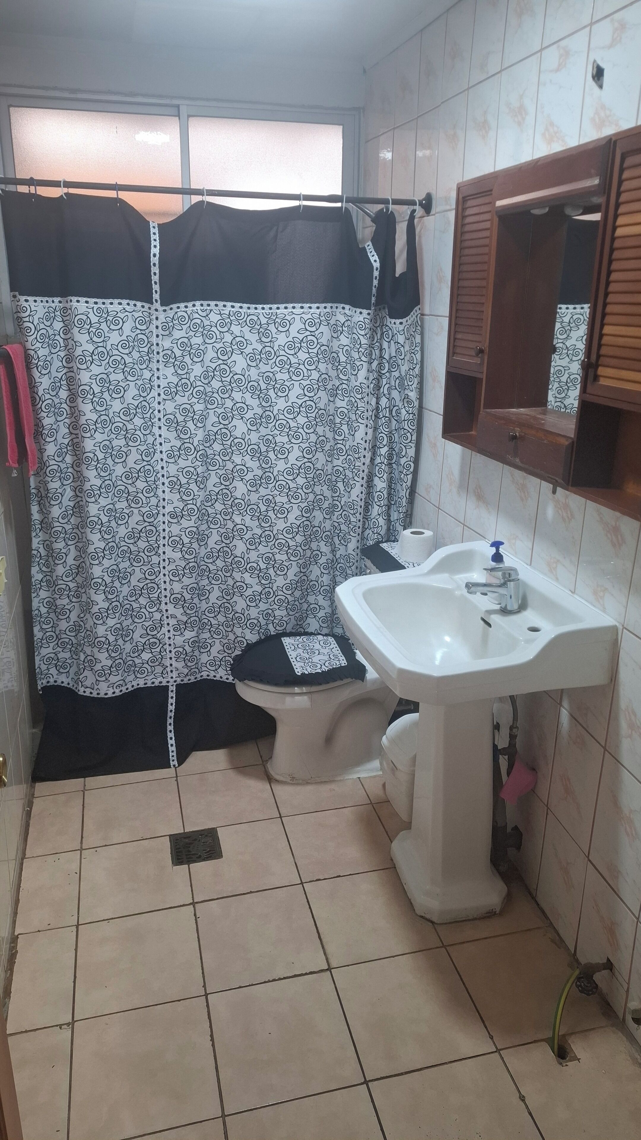 Un baño con inodoro, lavamanos y cortina de ducha.