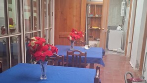 Ein Essbereich mit Tischen, die mit blauen Tischdecken bedeckt sind, Holzsesseln und einer Vase mit roten Blumen.