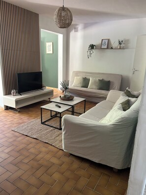 Ein Wohnzimmer mit einer Couch, einem Fernseher auf einem Schrank, einem Couchtisch und einer Pendelleuchte.