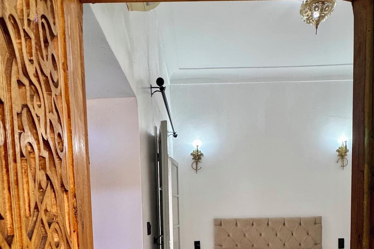 Ein Schlafzimmer mit einem Bett, einem wandmontierten Fernseher und einer dekorativen Holzvertäfelung.
