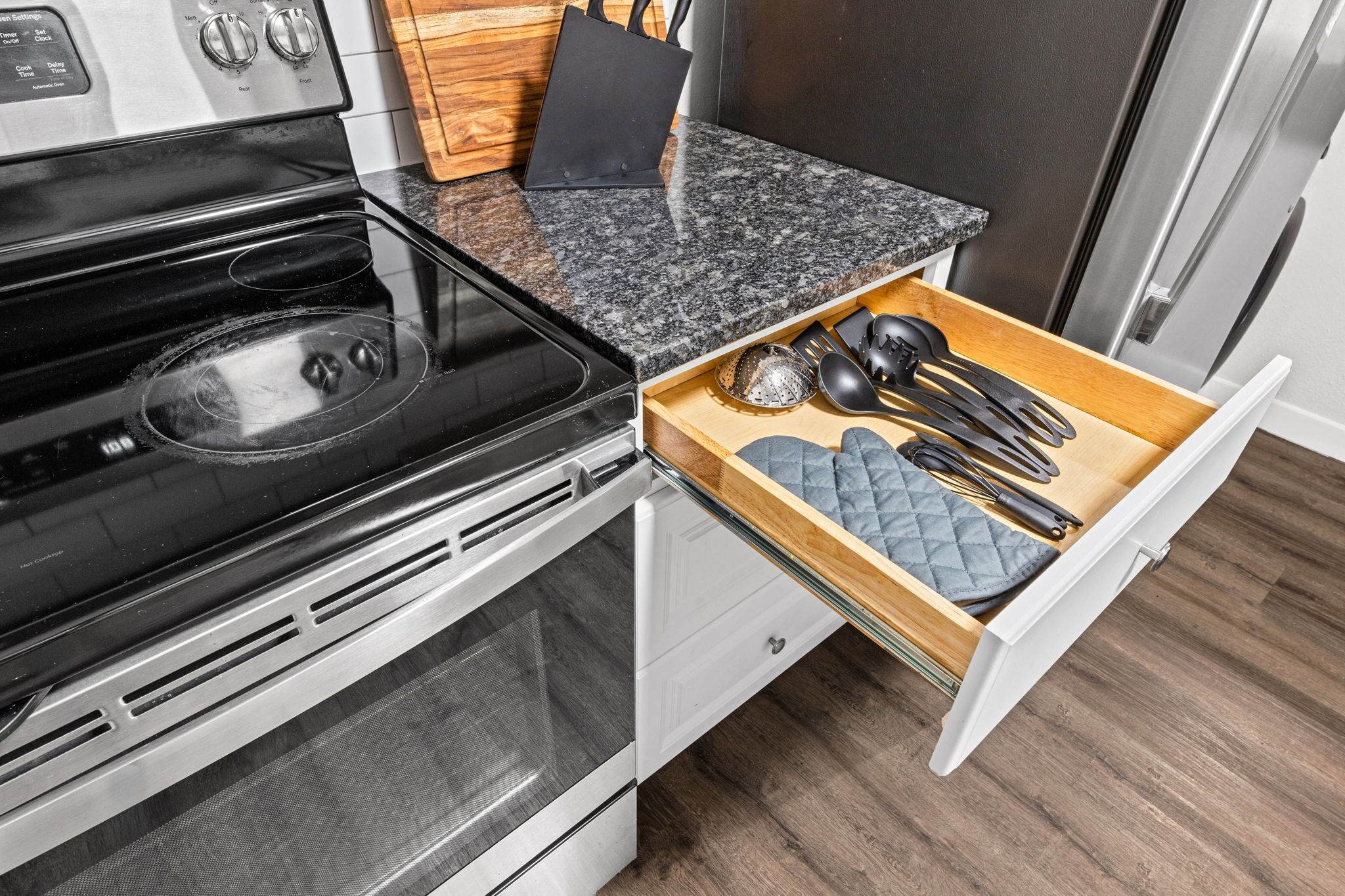 Una cucina con piano cottura nero, elettrodomestici in acciaio inossidabile e un organizer a cassetti con utensili.