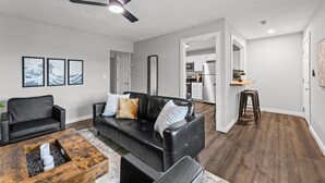 A living room with a black leather sofa, a wooden coffee table, and a ceiling fan.