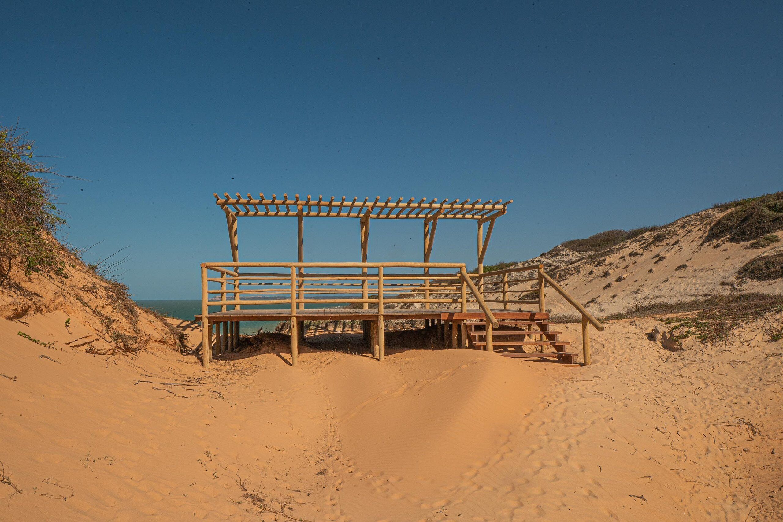 A wooden beach structure with a bench and a staircase.