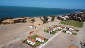 A coastal area with white buildings, sandy terrain, and a view of the ocean. - Beach Estates com Piscina Privativa By Carpediem (Aracati)