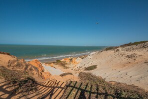Eine Küstenlandschaft mit Sandstrand, Felsen und blauem Himmel.