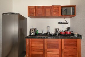 Eine Küche mit Holzausstattung, einem Edelstahlkühlschrank, einer Mikrowelle, einer Kaffeemaschine und einem Mixer.