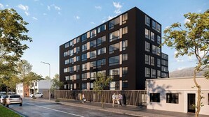 A modern multi-story building with a flat roof, large windows, and a simple facade.