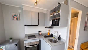 A compact kitchen with built-in appliances, a microwave, and a sink.