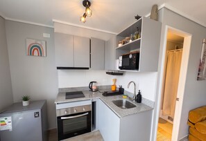 Una cocina compacta con electrodomésticos integrados, un microondas y un lavamanos.