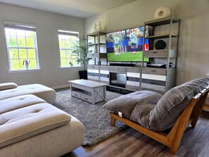 A living room with a TV, sofa, and wooden entertainment unit. - Stunning Lake View Home - Family Retreat (Winston-Salem)