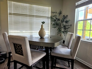 A dining area with a round table, two upholstered chairs, a vase, and a potted plant. - Stunning Lake View Home - Family Retreat (Winston-Salem)