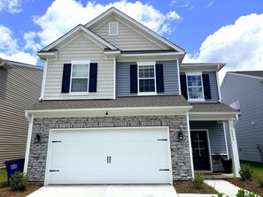 A two-story house with a stone facade, a white garage door, and a blue mailbox. - Stunning Lake View Home - Family Retreat (Winston-Salem)