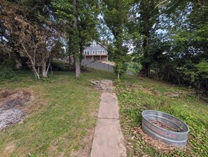 Ein Wohngebiet mit einem Weg, der zu einem Haus führt, umgeben von Bäumen und einem Metallfass.