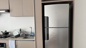 Ett modernt kök med ett kylskåp i rostfritt stål, en inbyggd ugn och en gasspis.