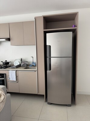 A modern kitchen with a stainless steel refrigerator, a built-in oven, and a gas stove. - English seagull cover (Florianópolis)
