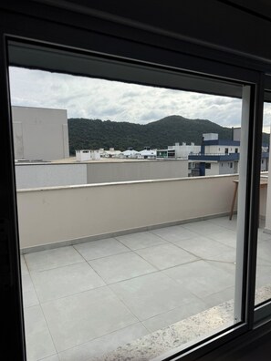 A balcony with a tiled floor, a view of buildings, and a mountain in the background. - English seagull cover (Florianópolis)