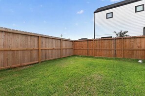Ein eingezäunter Garten mit Rasenfläche und einem Fußball.