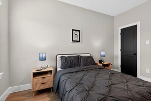 Ein Schlafzimmer mit einem Bett, zwei Nachttischen, einem Wandlichtschalter und einer Tür.